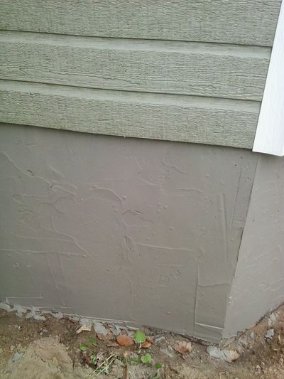 Fresh crépi trowelled onto the foundation wall, still wet.