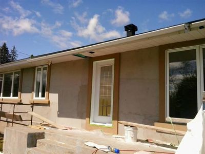 Wide view of the bungalow mid-job with the base coat applied.