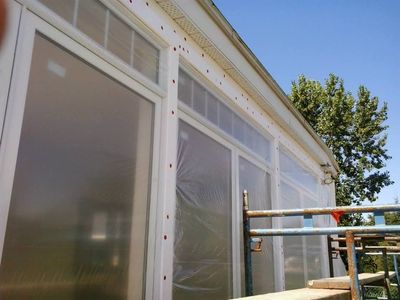 Wall preparation: mesh fastened to substrate and windows masked with plastic sheeting.